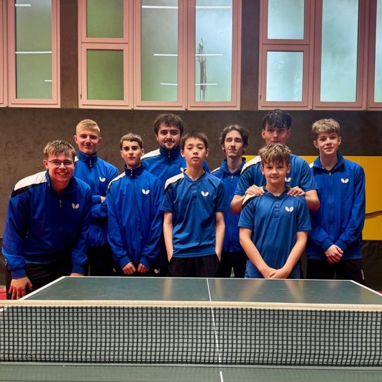 Gruppe junger Tischtennisspieler in blauen Т-Shirts vor einem Vereinshaus. Gruppe junger Tischtennisspieler in blauen Т-Shirts vor einem Vereinshaus.