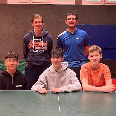 Gruppe junger Tischtennisspieler in blauen Т-Shirts vor einem Vereinshaus.