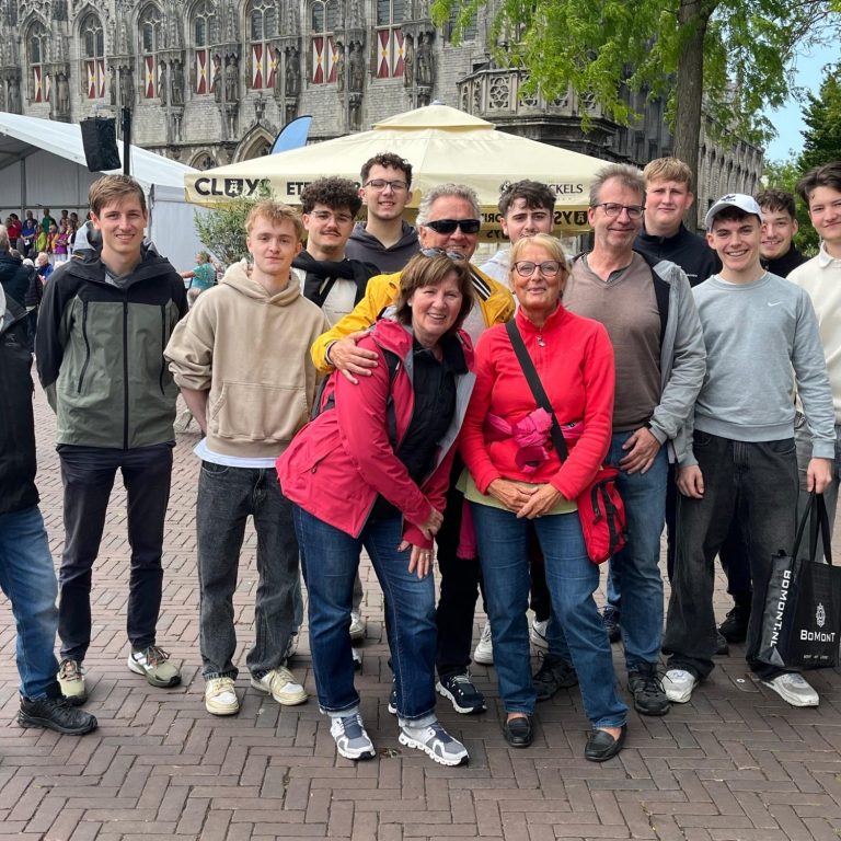 Gruppe von Jugendlichen in blauen Sportshirts vor einem Tischtenniszentrum.