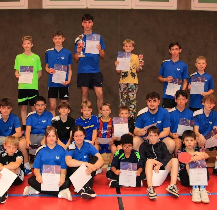 Gruppe junger Tischtennisspieler in blauen Т-Shirts vor einem Vereinshaus.