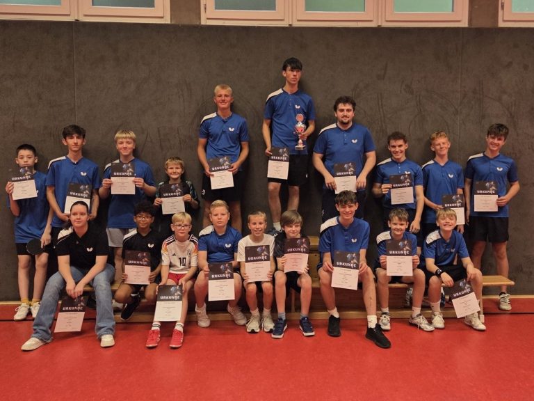 Gruppe junger Tischtennisspieler in blauen Т-Shirts vor einem Vereinshaus.