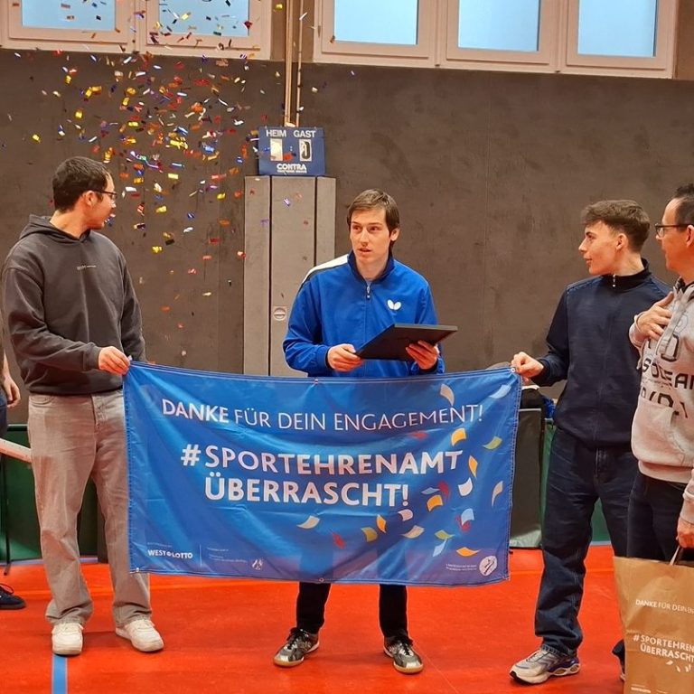 Gruppe junger Tischtennisspieler in blauen Т-Shirts vor einem Vereinshaus.