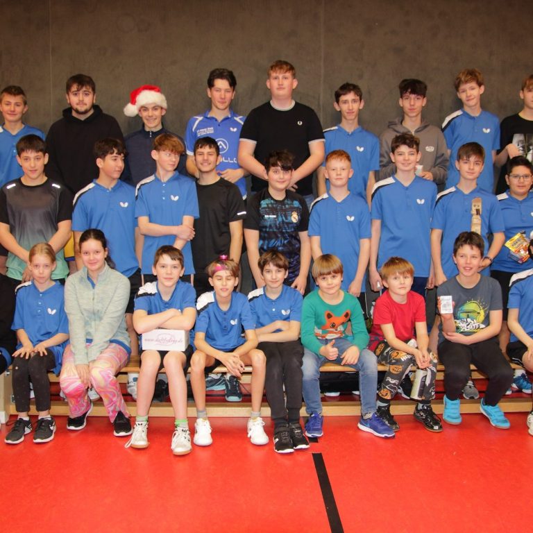 Gruppe junger Tischtennisspieler in blauen Т-Shirts vor einem Vereinshaus.